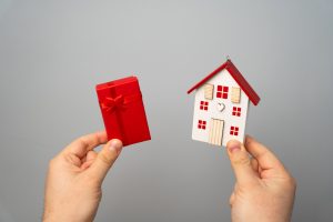 Man holds a miniature house and gift box
